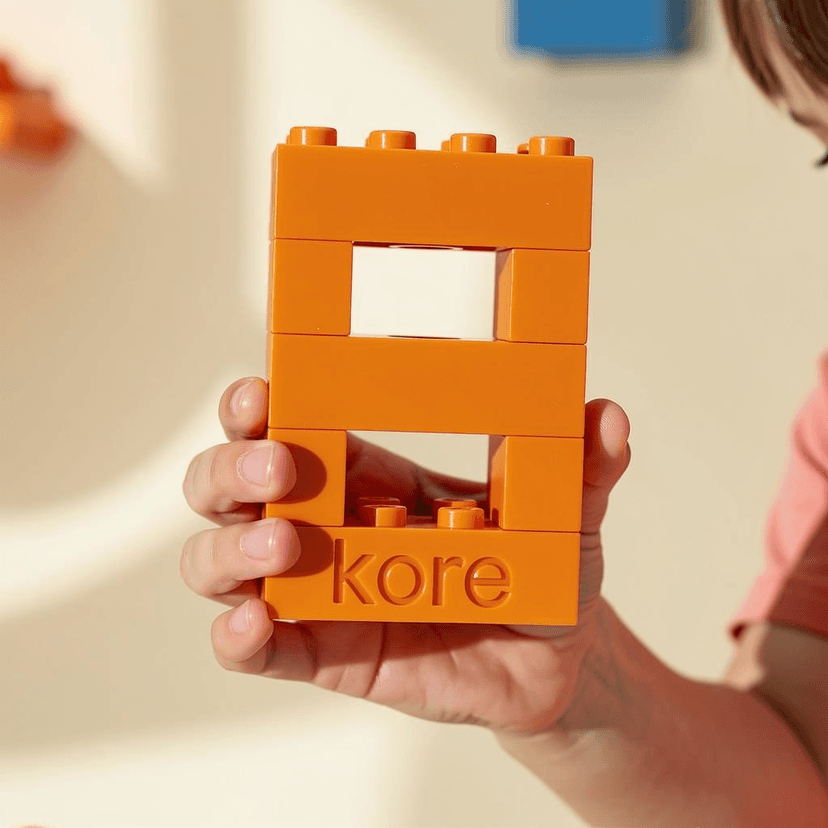 A child's hand holding a hand-sized SecondCycle brick